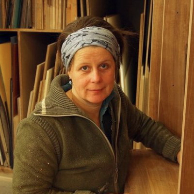Christina Kundert in ihrer Werkstatt vor einem Regal mit Holzplatten